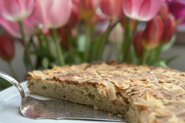 Kuchen auf Platte mit Tulpen im Hintergrund