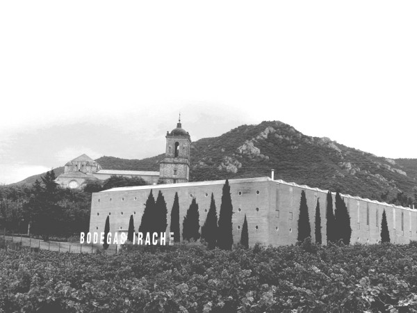 Bild eines Klosters und Weinguts, im Hintergrund ein Berg, im Vordergrund Weinberge