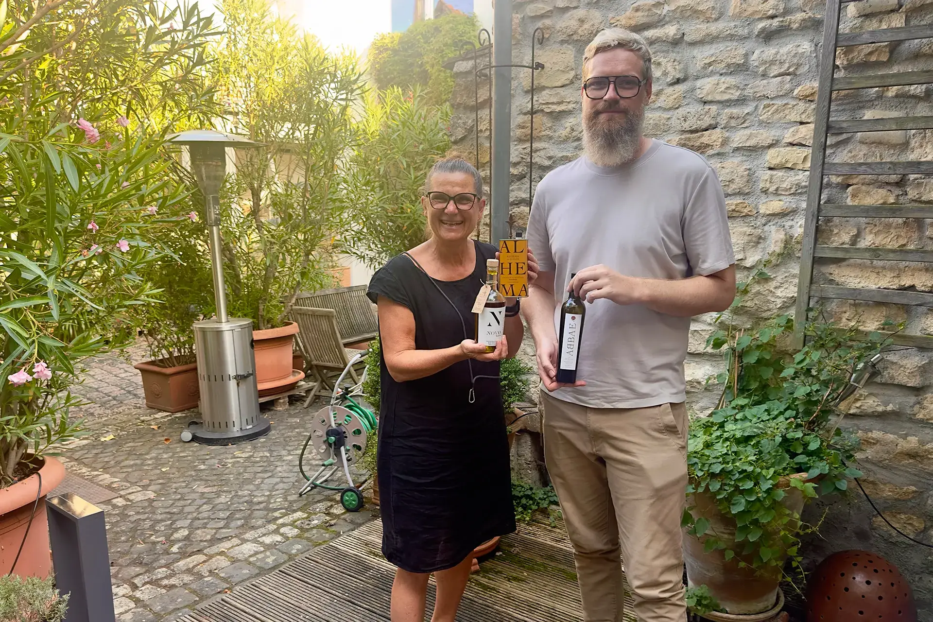 Mann und Frau stehen vor einer Wand und halten Olivenöl in der Hand