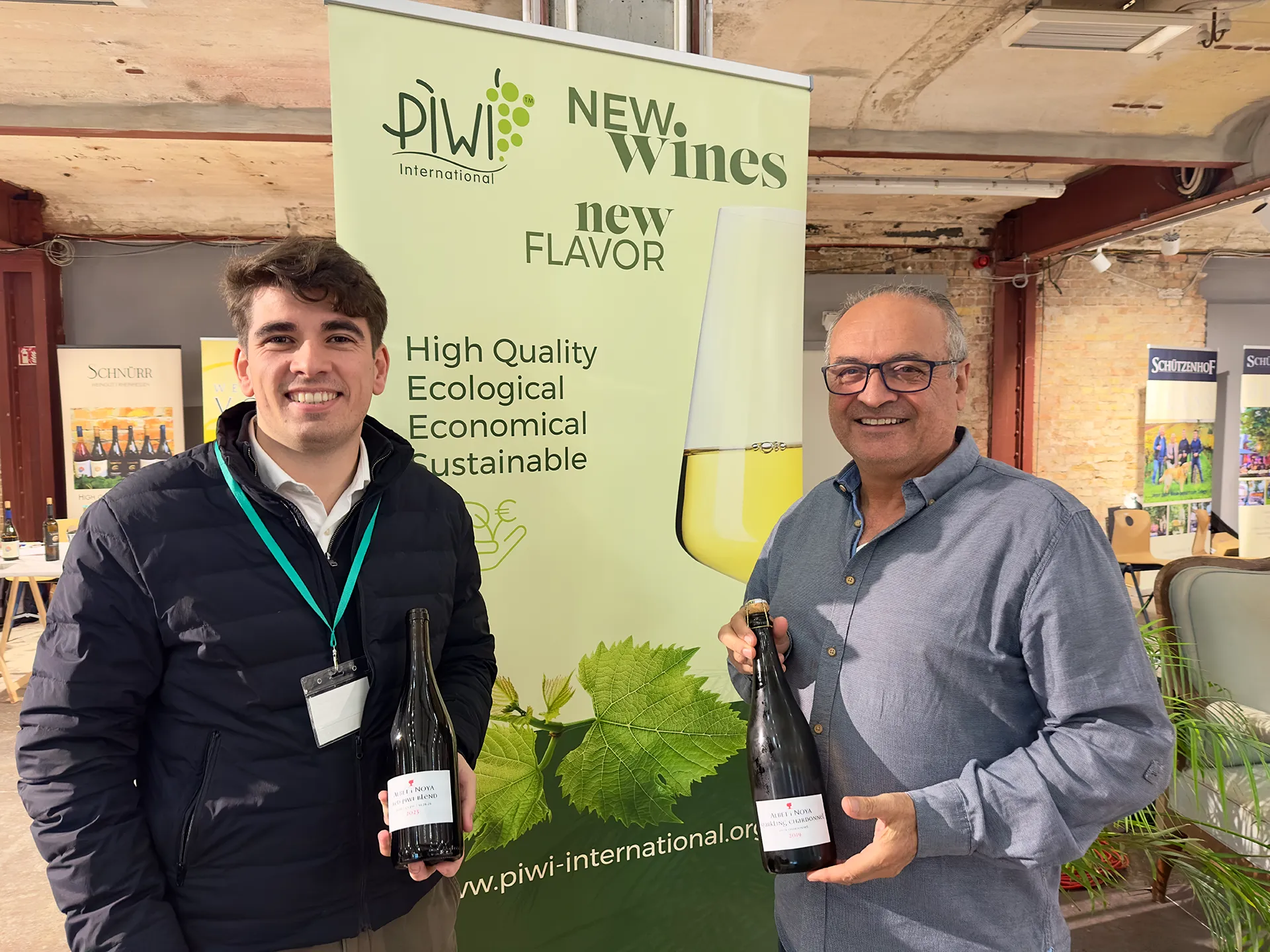 Zwei Männer stehen vor einem Plakat für PIWI Weinreben