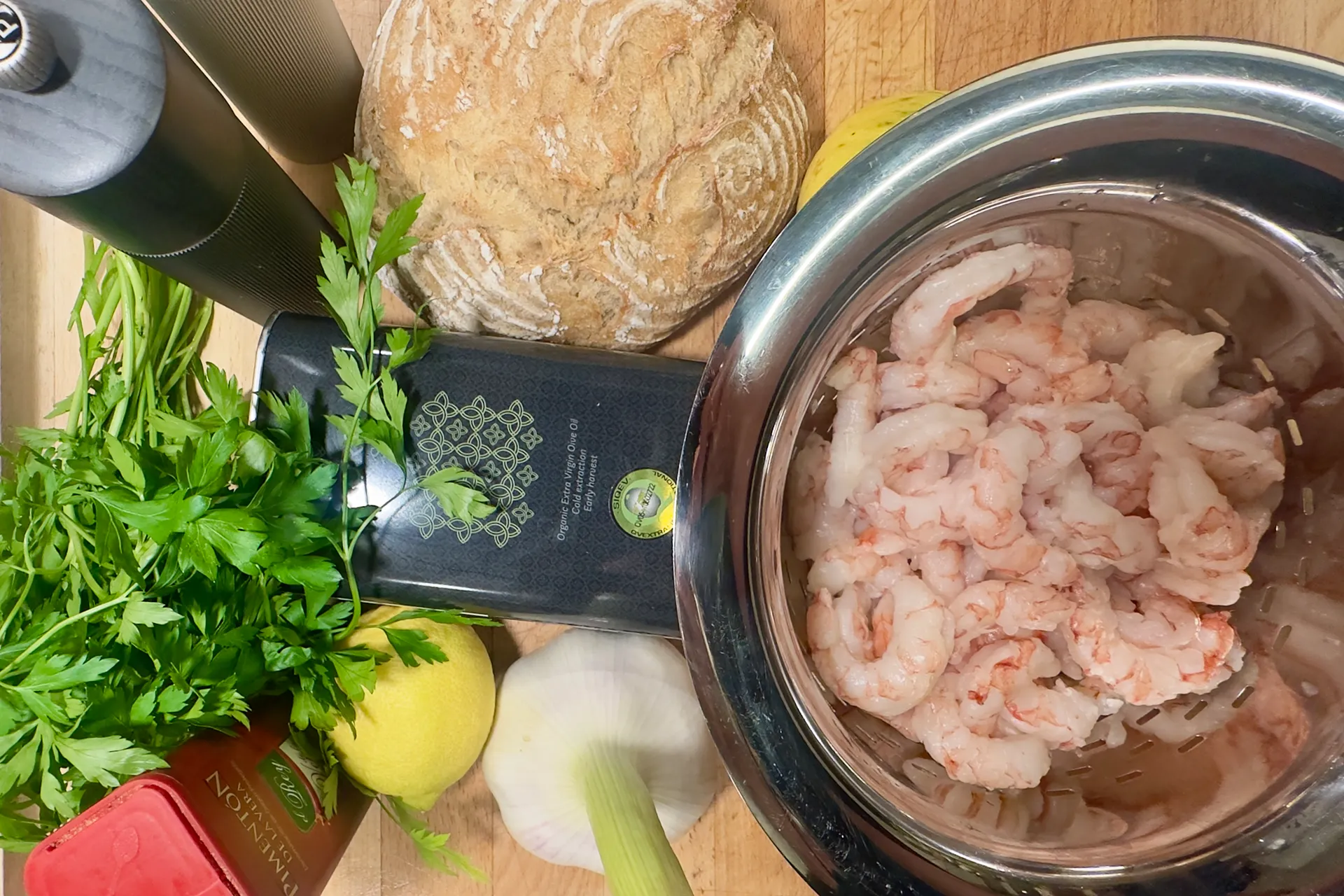 Auf einem Holzbrett stehen alle Zutaten die man für spanische Knoblauchgarnelen benötigt