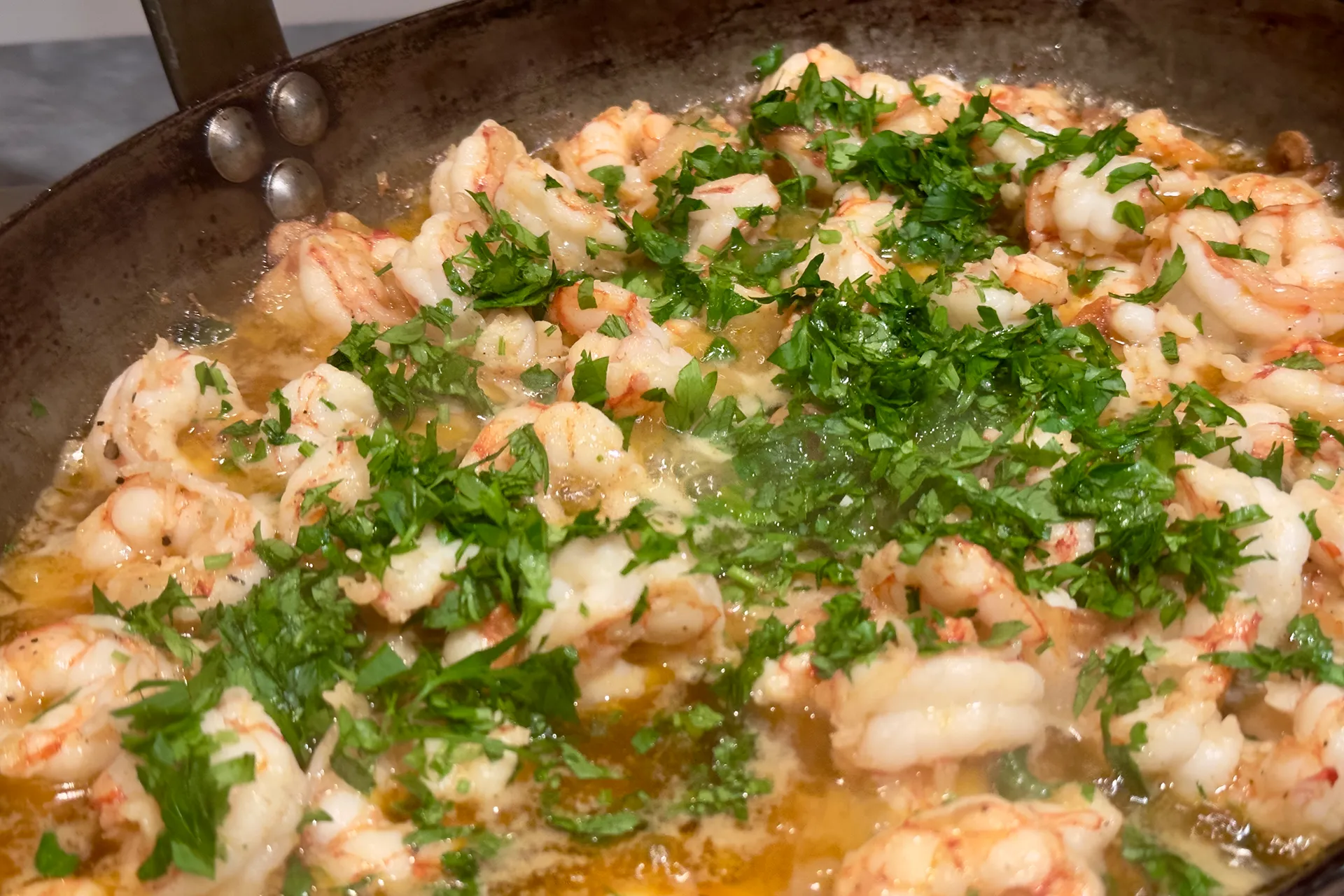 Eine gusseiserne Pfanne mit Garnelen und Petersilie