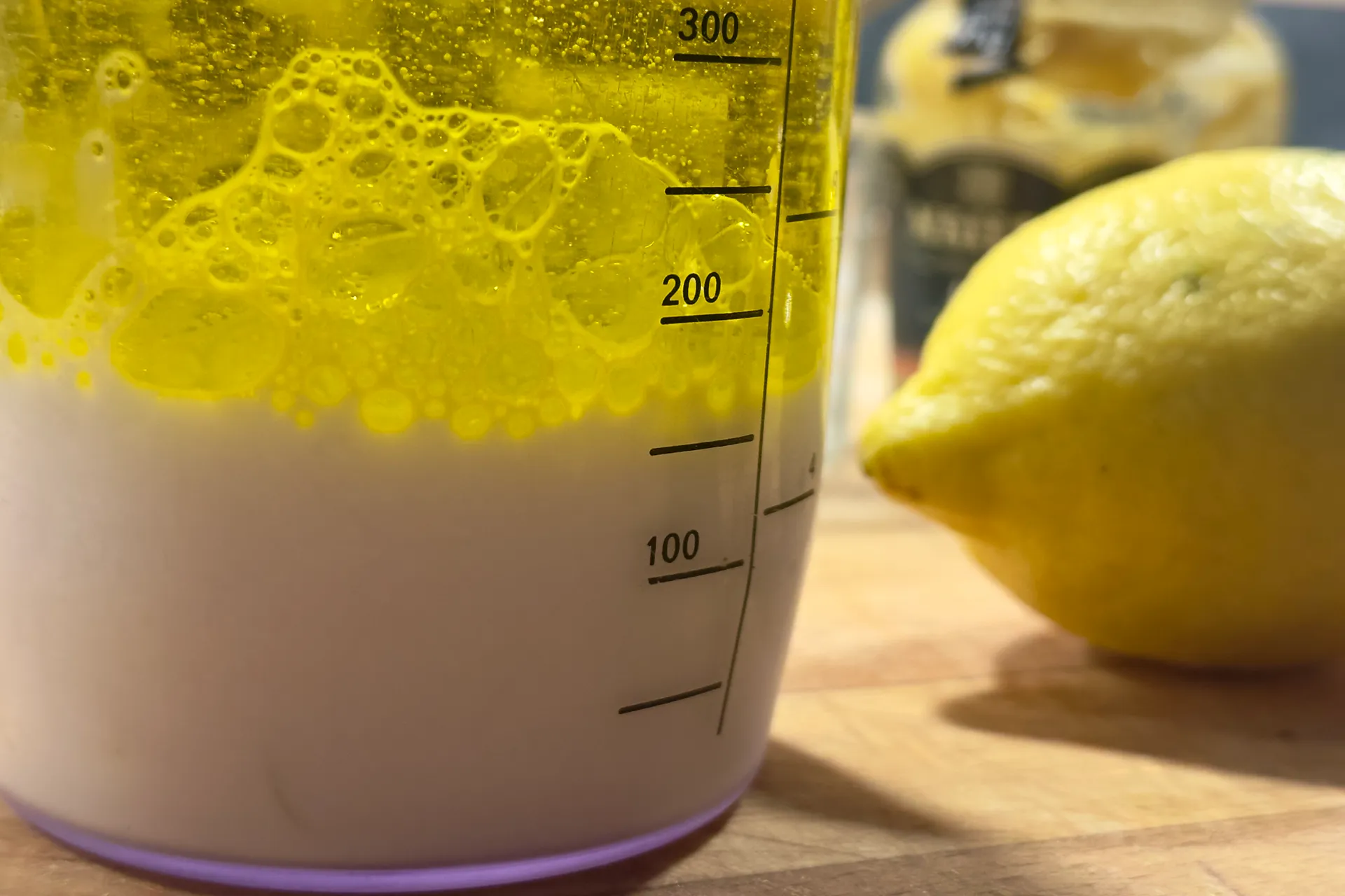 Ein Messbecher nebendran liegt eine Zitrone in der Messbecher ist Milch und Öl