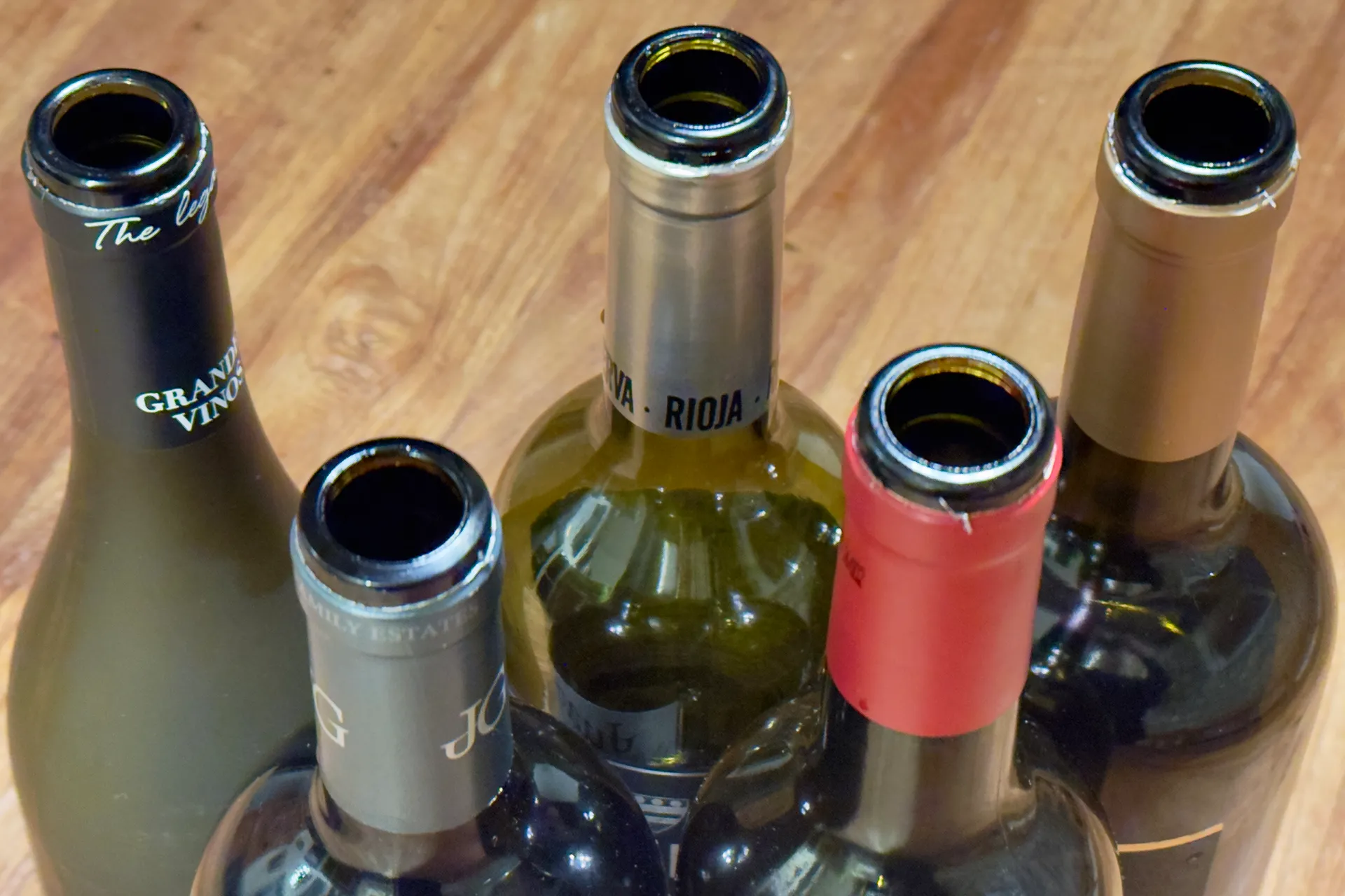 Fünf Weinflaschen von oben mit den Öffnungen