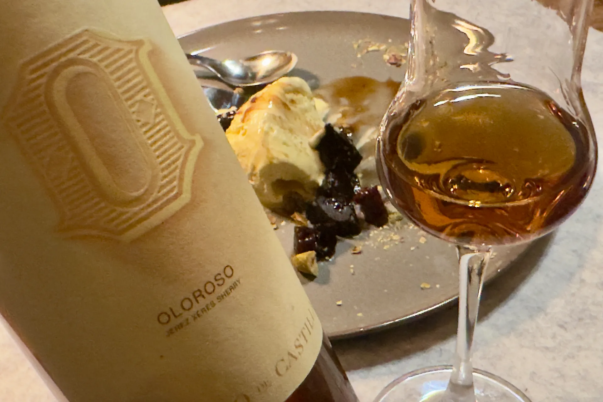 Eine Flasche Sherry mit Glas und Vanilleeis im Hintergrund