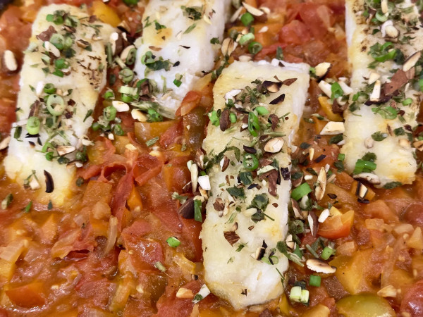Fischfilets in einer Pfanne mit Tomatensauce und Kräuter Mandel Topping