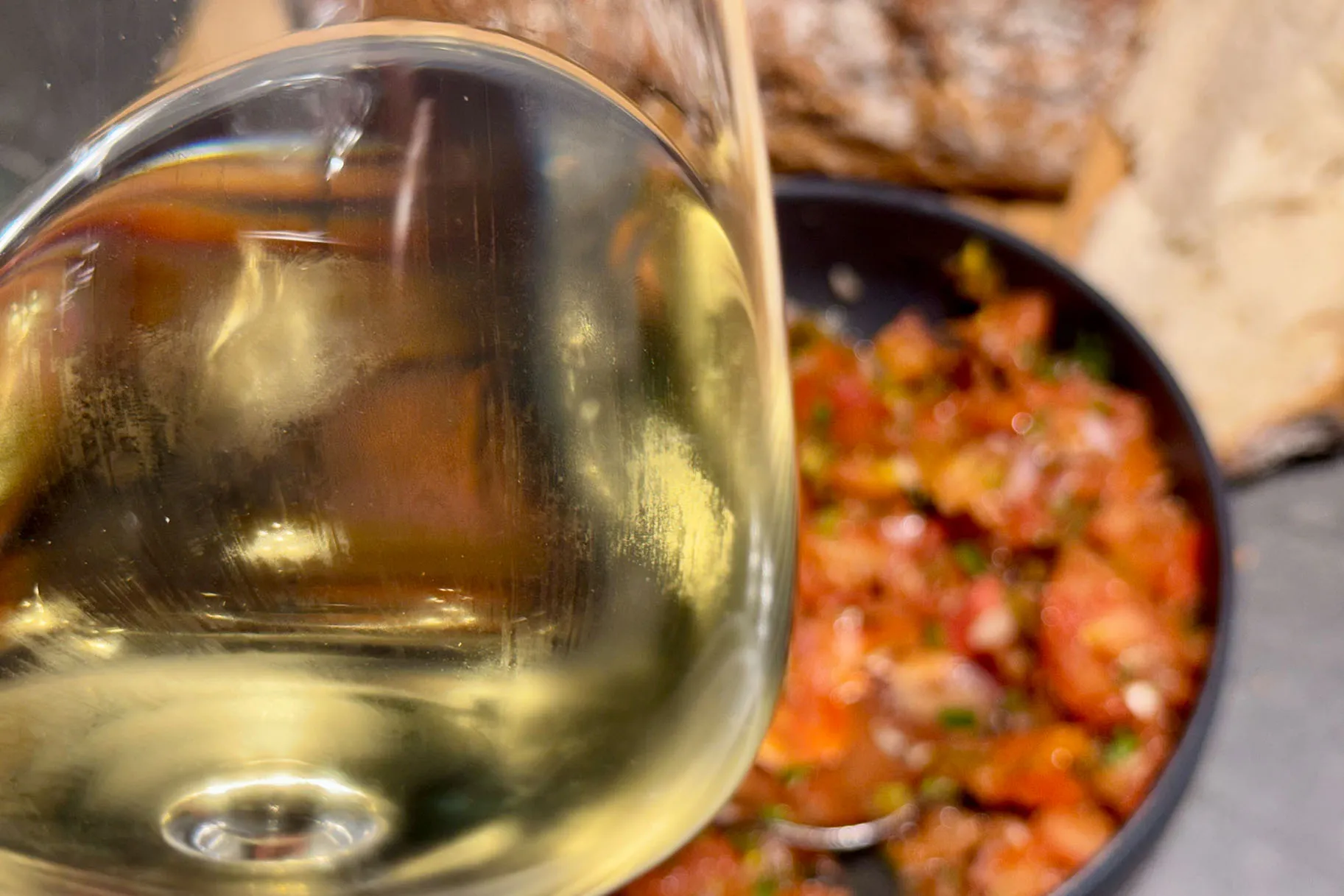 Weinglas mit Manzanilla im Vordergrund, dahinter Schale mit Tomatensalsa und Brot