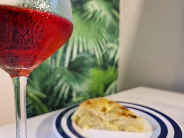 Ein beschlagenes Glas Wein und im Hintergrund Tapas